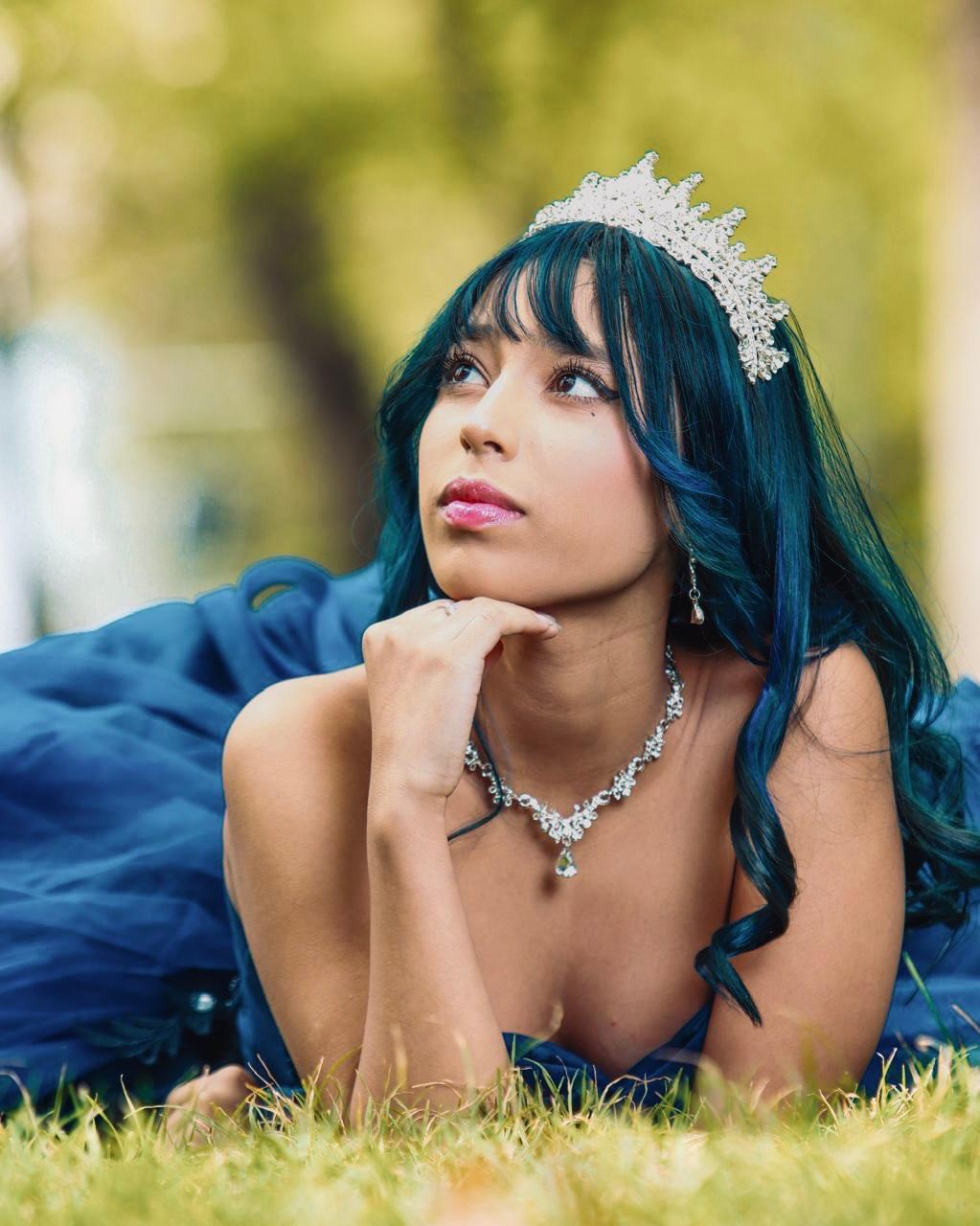 Barbara Gabriela con su corona plateada y vestido azul en el jardín